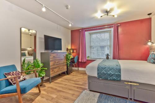 a bedroom with red walls and a bed and a tv at The Apple Loft Rooms in Ambleside