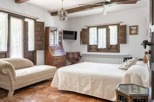 a bedroom with a bed and a chair and windows at Venta del Celemín in Ossa de Montiel