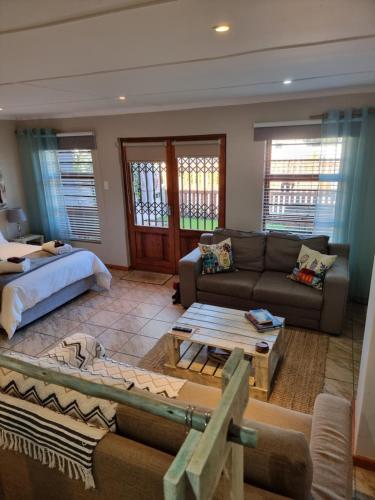 een woonkamer met een bank en een bed bij Dolphins Self-Catering Accommodation in George