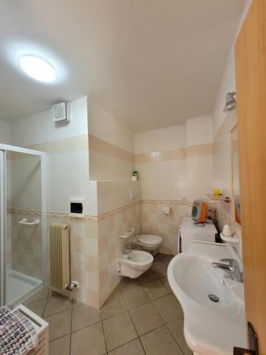 y baño con 2 aseos, lavamanos y ducha. en Appartamento "Laghet" a piano terra con giardino, en Coredo