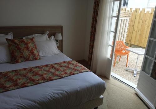 a bedroom with a bed and a door to a balcony at Hôtel Le Gois in Beauvoir-sur-Mer
