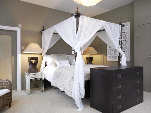 a bedroom with a canopy bed with white curtains at Windfalls Boutique Hotel in Crawley