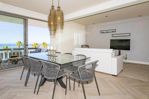 a dining room with a glass table and chairs at Quarteira Beach Stunning Apartment in Quarteira