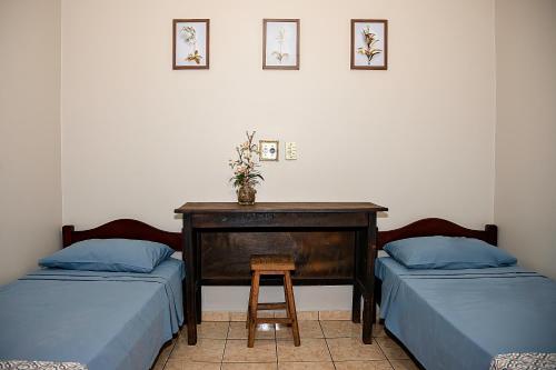 a room with two beds and a table with a stool at RP HOTEL in Ribeirão Preto