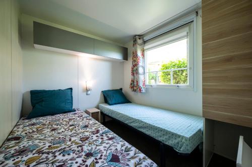 a small bedroom with a bed and a window at Charmant camping Familiale 3 Etoiles vue 360 plage piscine à débordement empl XXL in Labeaume