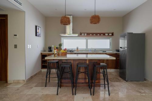 a kitchen with a island with bar stools and a refrigerator at Valhalla Residences by Biwa in Tulum