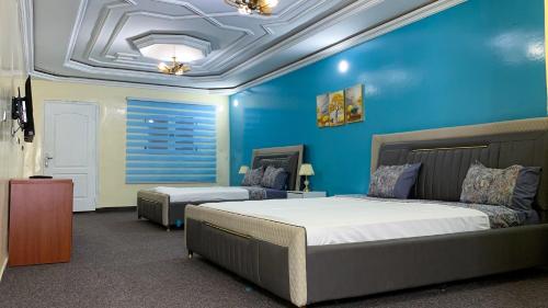 a bedroom with a bed and a blue wall at Hotel Suites TALHAYA, NOUAKCHOTT in Nouakchott