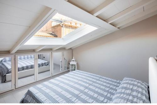 Schlafzimmer im Dachgeschoss mit einem Bett und einem Dachfenster in der Unterkunft Maison del Ducato “Cavour 24” in Parma