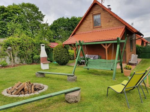 a house with a green bench and chairs in a yard at Domki Niesiołowice in Niesiołowice