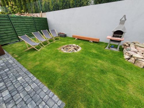 two chairs and a bench in a yard with a fire pit at Domki Niesiołowice in Niesiołowice