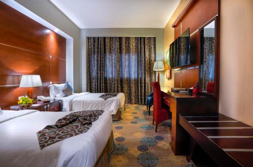 Habitación de hotel con 2 camas y escritorio en La Fontaine Jeddah Hotel, en Yeda