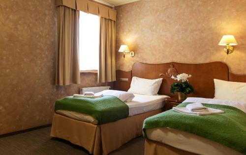 ポズナンにあるHotel Księcia Józefaのホテルルーム ベッド2台&緑の毛布付