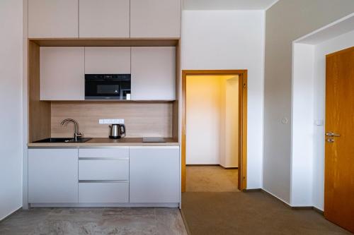 a kitchen with white cabinets and a sink at Relax Hotel Stork in Lednice