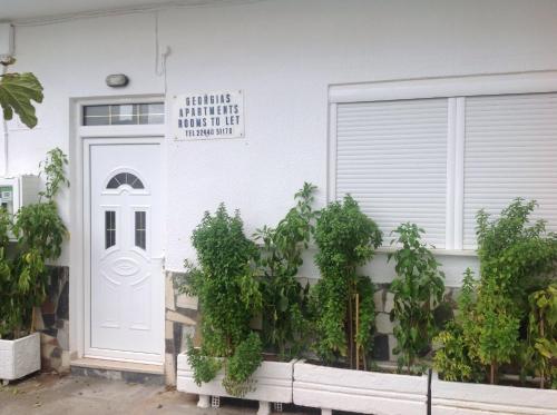 a white house with a white door and plants at Georgias Apartments in Haraki