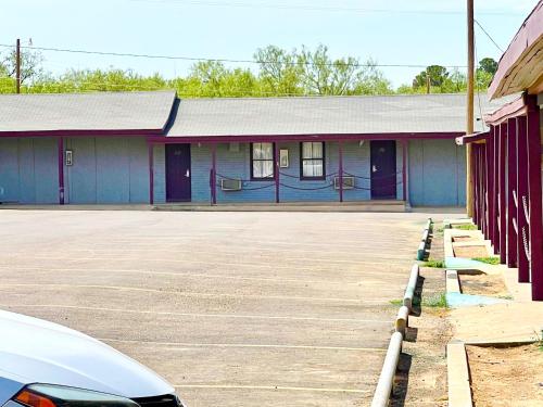 a building with blue doors and a parking lot at Bradbury Inn in Big Spring