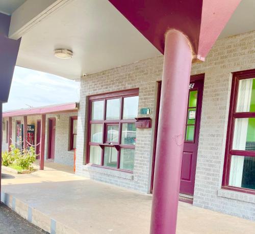 a pink pole in front of a building with a purple door at Bradbury Inn in Big Spring