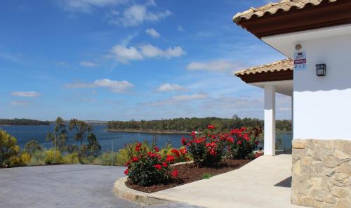 een uitzicht op een meer vanuit een huis met bloemen bij Casa Rural encantos de Orellana in Navalvillar de Pela