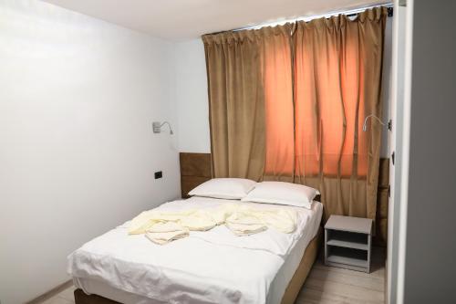 Schlafzimmer mit einem Bett mit weißer Bettwäsche und einem Fenster in der Unterkunft Casa 5ive in Tăşnad