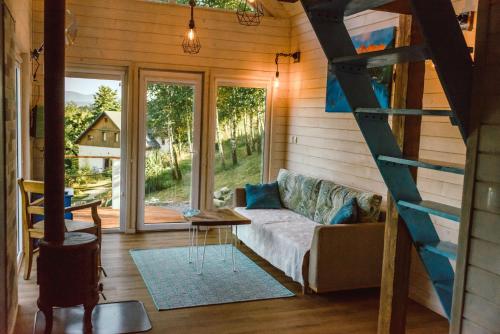 ein Wohnzimmer mit einem Sofa und einer Leiter in der Unterkunft Lazurowe Love - domek na odludziu z widokami in Jaszczurowa