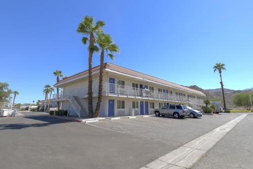 a hotel with palm trees and a car parked in a parking lot at Motel 6-Rancho Mirage, CA - Palm Springs in Rancho Mirage