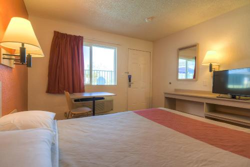 a hotel room with a bed and a desk and a television at Motel 6-Rancho Mirage, CA - Palm Springs in Rancho Mirage