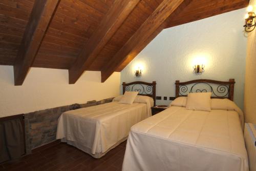 two beds in a room with wooden ceilings at Casa Rural Perico in Fiscal