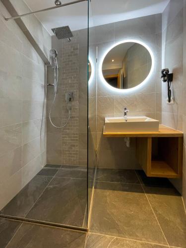a bathroom with a shower and a sink and a mirror at Hotel & Suites Glück Auf in Mayrhofen