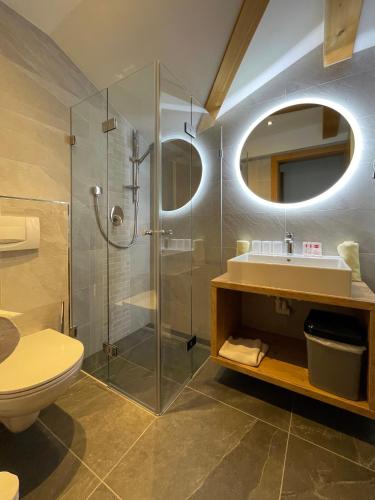a bathroom with a shower and a toilet and a sink at Hotel & Suites Glück Auf in Mayrhofen