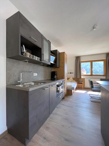 a kitchen with a sink and a living room at Hotel & Suites Glück Auf in Mayrhofen