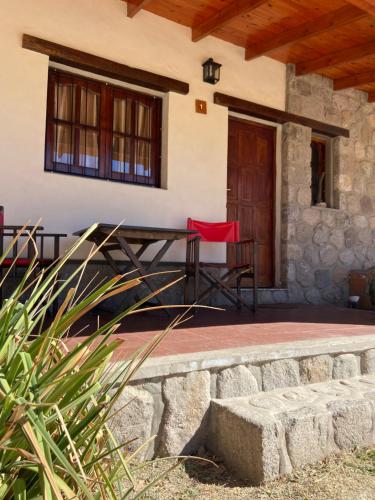 a patio with a table and a red chair in front of a house at Cabañas La Suyana in Tafí del Valle