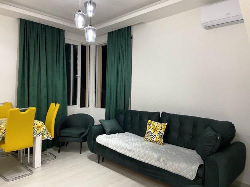 a living room with a green couch and yellow chairs at ID apartments in Tivat
