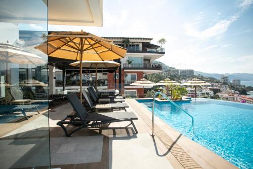 een zwembad met stoelen en parasols naast een gebouw bij Pinnacle Resorts 179 - Adults Only in Puerto Vallarta