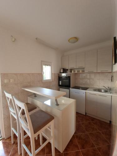 cocina con armarios blancos, mesa y sillas en Guest House Ivana, en Tivat