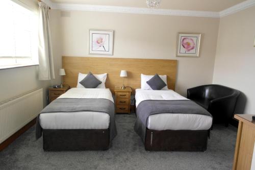 a hotel room with two beds and a chair at Seacourt Accommodation Tramore - Adult Only in Tramore