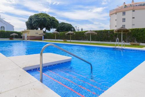 a large swimming pool with blue water and umbrellas at CasaBel - Playa in Torrox Costa