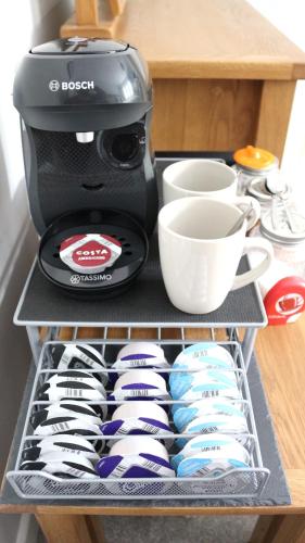 a black coffee maker and cups on a shelf at Romany Cottage B&B in Buckden