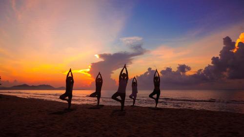 a group of people doing yoga on the beach at sunset at Holiday Inn Resort Ho Tram Beach by IHG in Ho Tram
