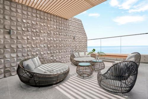 a patio with chairs and tables and a wall with the ocean at Holiday Inn Resort Ho Tram Beach by IHG in Ho Tram