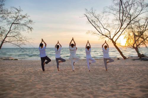 a group of women doing yoga on the beach at Crowne Plaza Phu Quoc Starbay by IHG in Phu Quoc