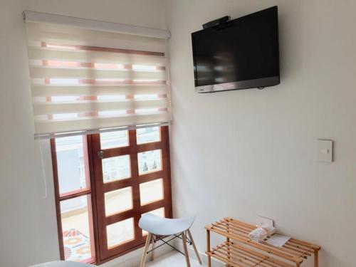 a room with a television and a chair and a window at Luna Nueva Casa de Huéspedes in Ríohacha
