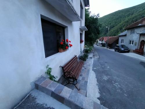 a bench next to a building with flowers in a window at Casa Tâmplarului 