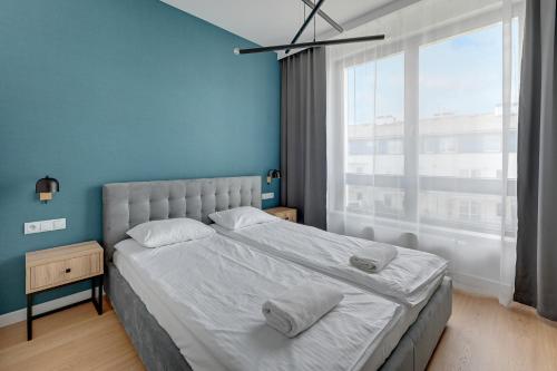 sypialnia z białym łóżkiem i dużym oknem w obiekcie Baltic Lagoon - Okrzei Residence w mieście Sopot
