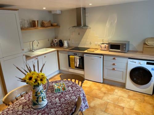 a kitchen with a table with a vase of flowers on it at Beck cottage in Rosedale Abbey
