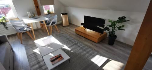 een woonkamer met een flatscreen-tv en een tafel en stoelen bij Klimatyczne apartamenty z widokiem na góry Sowie in Bielawa