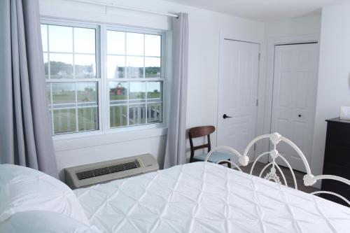 a white bedroom with a bed and a window at Gateway to Greenwich Suites in Saint Peters