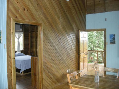 ein Schlafzimmer mit einem Bett und einer Holzwand in der Unterkunft Apartments Chez Milady in Utila
