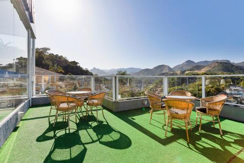 een patio met stoelen en tafels op een balkon bij Hotel Petropolis Inn in Petrópolis