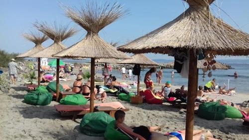 a group of people sitting on a beach with umbrellas at Valemar Apartments in Pomorie