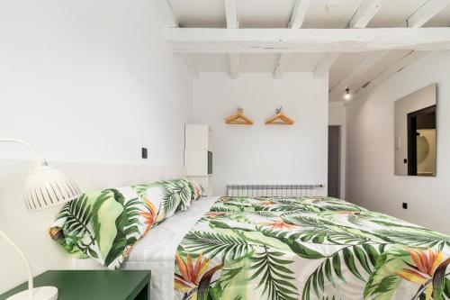 a white bedroom with a bed with green leaves at BENEDICTA FAMILY ROOMS in Suances