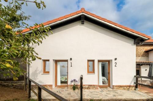 una casa bianca con il tetto rosso di BENEDICTA FAMILY ROOMS a Suances